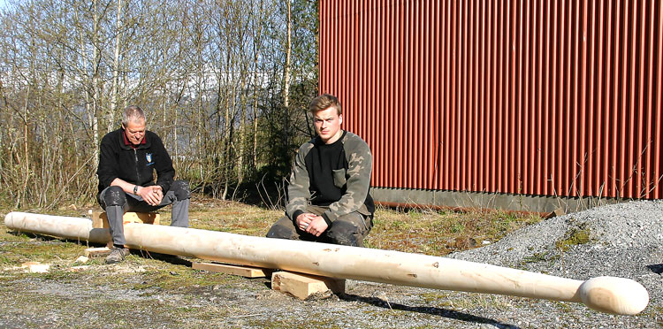 Per Kjell og Sindre Holtleite ved den åtte meter lange trommestikka dei har laga av ei gran.